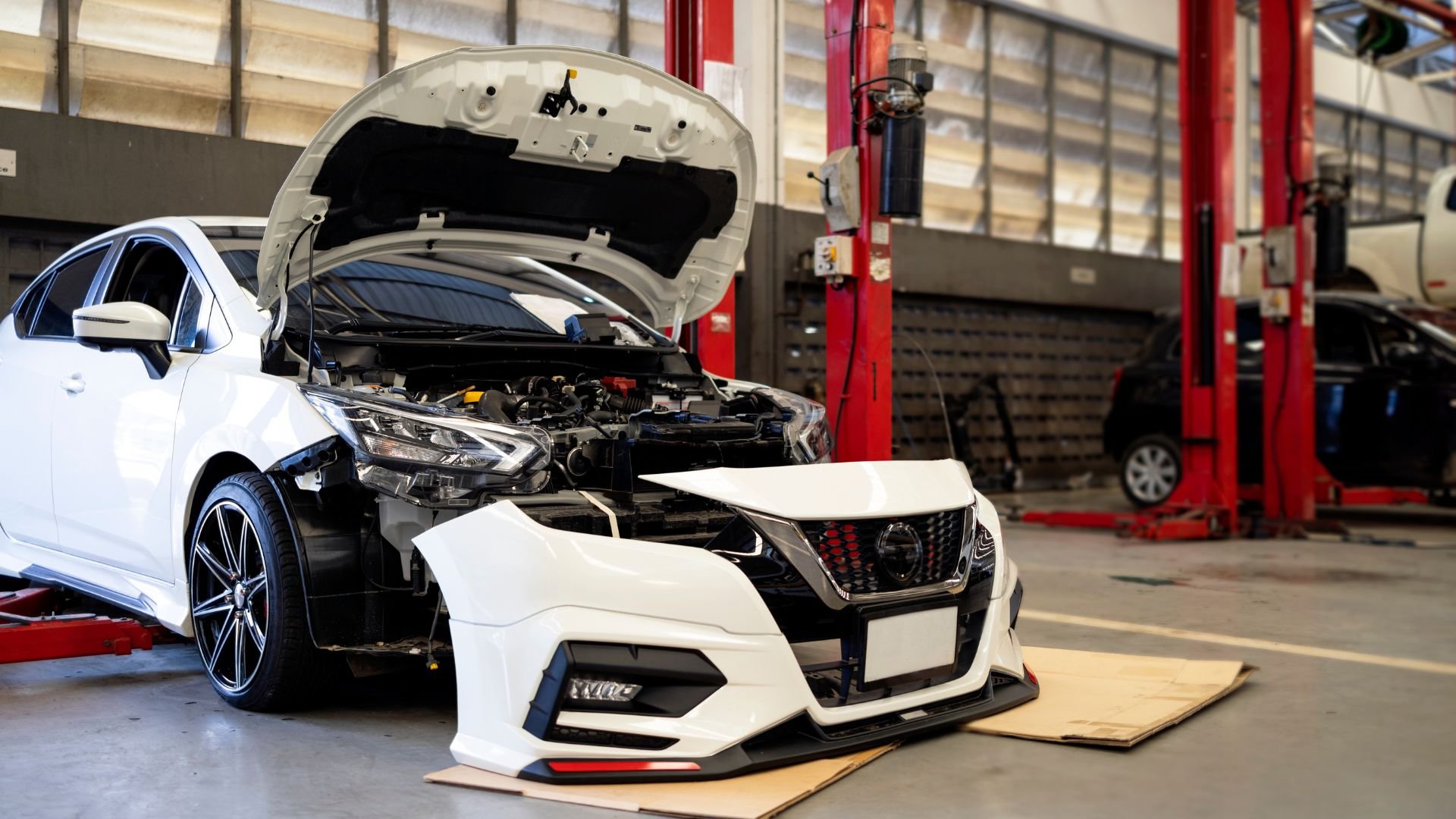 White car with open hood in auto repair shop getting maintenance