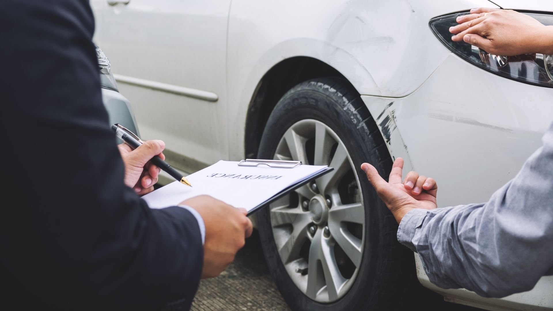 Insurance agent inspecting car damage and taking notes after accident